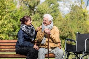 Elderly man with female caretaker on park bench