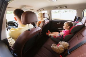 Child in car seat in back with parents riding in front of car