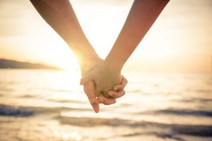 Couple holding hands on beach at sunset